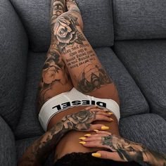 a tattooed woman laying on top of a couch