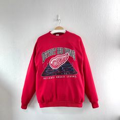 a red detroit red wings sweatshirt hanging on a wall