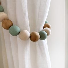 a white curtain with wooden beads hanging from it's side