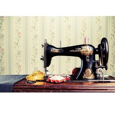 an old sewing machine sitting on top of a wooden table next to a wallpapered wall