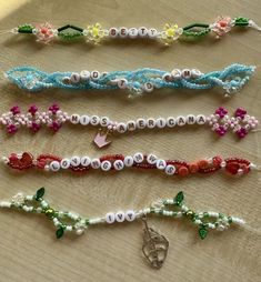 several bracelets are laid out on a wooden table with beads and charms attached to them