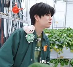 a young man in a green jacket is holding a stuffed animal and looking at something