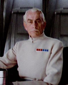 an older man sitting at a table with a cup in front of him on the plane