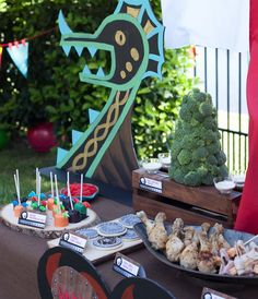 a table topped with lots of food next to a forest sign and trees in the background