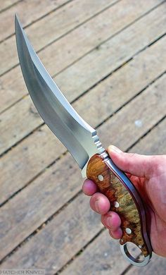 a hand holding a knife on top of a wooden floor