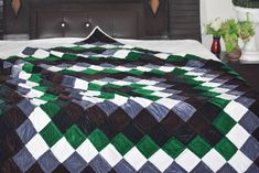 a bed with a green, white and black quilt on it