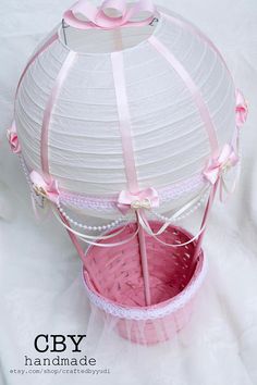 a pink basket with ribbon and bow on it sitting in front of a white background