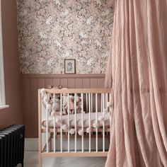 a baby's crib in front of a pink wallpaper