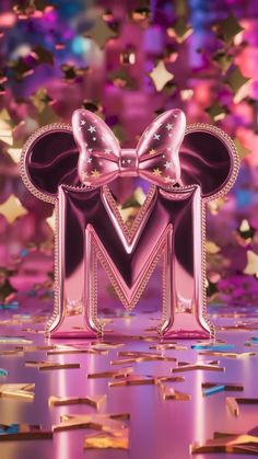 the letter m is made up of pink and gold foil with a large bow on top