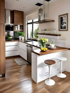 a modern kitchen with white cabinets and wood flooring is pictured in this image, there are two stools at the center of the island