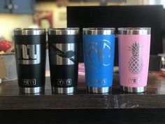 four different colored yeti cups sitting on top of a wooden table next to each other