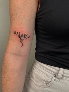 a woman's arm with the word balance tattooed in black ink on her left upper arm