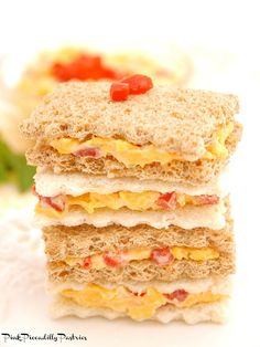 three sandwiches stacked on top of each other with eggs, cheese and tomato toppings