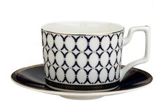 a coffee cup and saucer with an intricate design on the rim, set against a white background