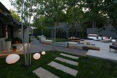 an outdoor patio with steps and lights in the grass, surrounded by trees on either side