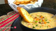 a black bowl filled with soup next to a piece of bread on top of a table