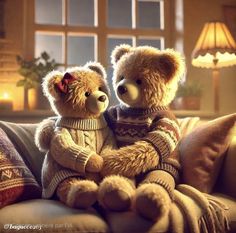 two teddy bears are sitting on a couch with their arms around each other, wearing sweaters