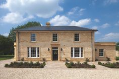 a large brick house sitting on top of a lush green field