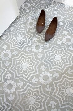 a pair of brown shoes sitting on top of a tiled floor