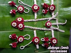 an arrangement of red and white flowers on a green leafy surface with beads in the middle