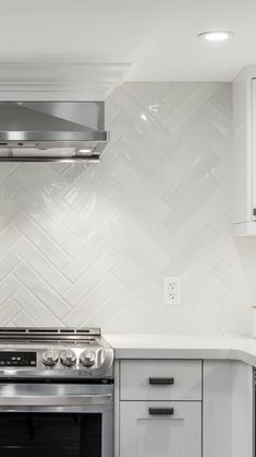 a stove top oven sitting inside of a kitchen next to white cupboards and drawers