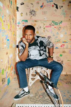 a man sitting on top of a chair next to a wall covered in graffiti and writing