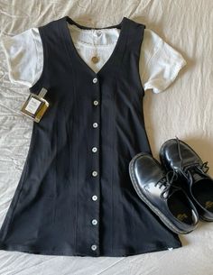 a pair of black shoes sitting on top of a bed next to a white shirt