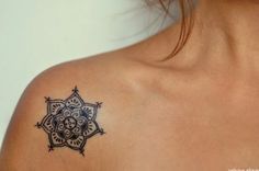 the back of a woman's shoulder with an intricate tattoo design on her upper arm