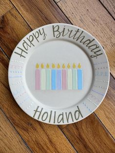 a white plate with candles on it that says happy birthday holland and has writing on the front