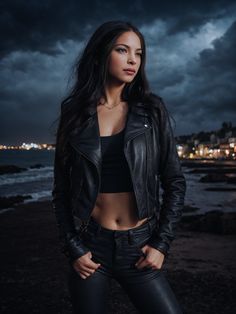 a beautiful young woman standing on top of a beach next to the ocean at night