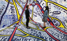 two people are standing in front of a large piece of art that looks like they are looking at each other