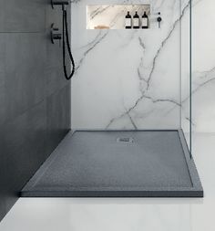 a bathroom with marble walls and flooring, including a walk in shower that has glass doors