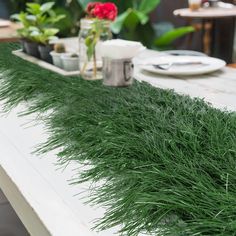 the table is covered with green grass on it's sides and flowers in vases to the side