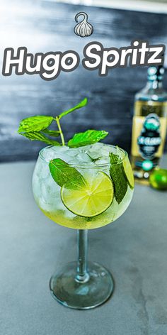 a close up of a drink in a glass on a table with limes around it