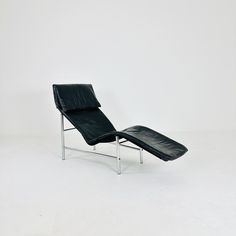 a black leather chaise lounge chair against a white background