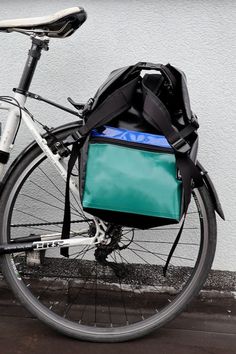 a bicycle parked next to a building with a blue bag on the front rack and seat