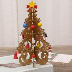 a small wooden christmas tree with bells on it's sides and an ornament hanging from the top