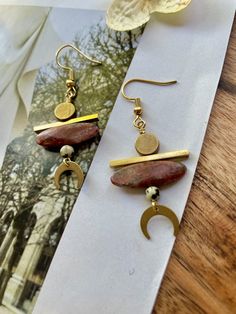 These are beaded, boho-style, mini crescent moon statement earrings featuring genuine red jasper rice beads, dalmatian jasper, and brass geometric pendants and connectors.These unique statement earrings hang approximately 2.25" inches from the lobe and measure about 1.0" inches across their widest point. They feature an 18k gold plated fishhook closure. These earrings are lightweight and should be suitable for everyday wear.Please see my other listings for all styles within this collection. Earthy Earrings, Beach Jewelry Boho, Earring Inspiration, Mini Earrings, Craps, Dalmatian Jasper, Rice Bead, Bold Jewelry, Beading Ideas