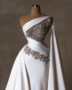 a white wedding dress with silver beading on the shoulders and neckline, draped over a mannequin