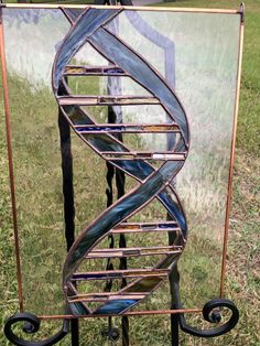 a metal spiral sculpture sitting on top of a grass covered field