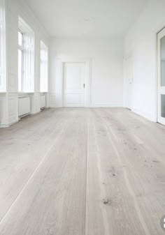 an empty room with white walls and wood floors