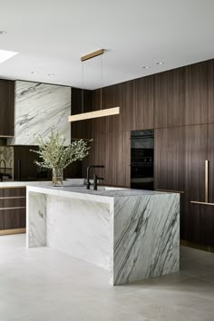 a large kitchen with marble counter tops and wooden cabinetry, along with an island in the middle