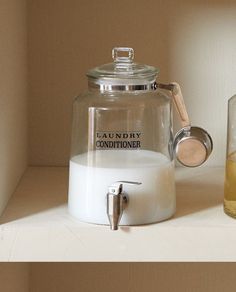 a glass teapot sitting on top of a white counter next to a cup filled with liquid