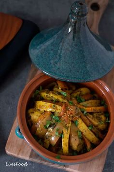 a pot filled with food sitting on top of a wooden cutting board