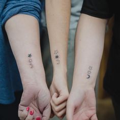 two people holding hands with stars and moon tattoos on their arms