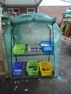 several baskets are stacked on top of each other in front of a green structure with mesh netting