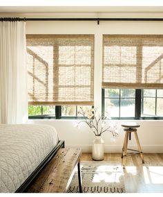 a bedroom with white walls and wooden blinds