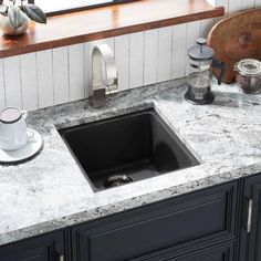 a kitchen sink sitting on top of a counter next to a coffee pot and cup