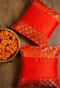 two red pillows and a bowl of food on a wooden table next to each other