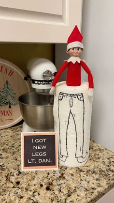 an elf is sitting on top of a large roll of toilet paper and next to a sign that says i got new legs lt dan